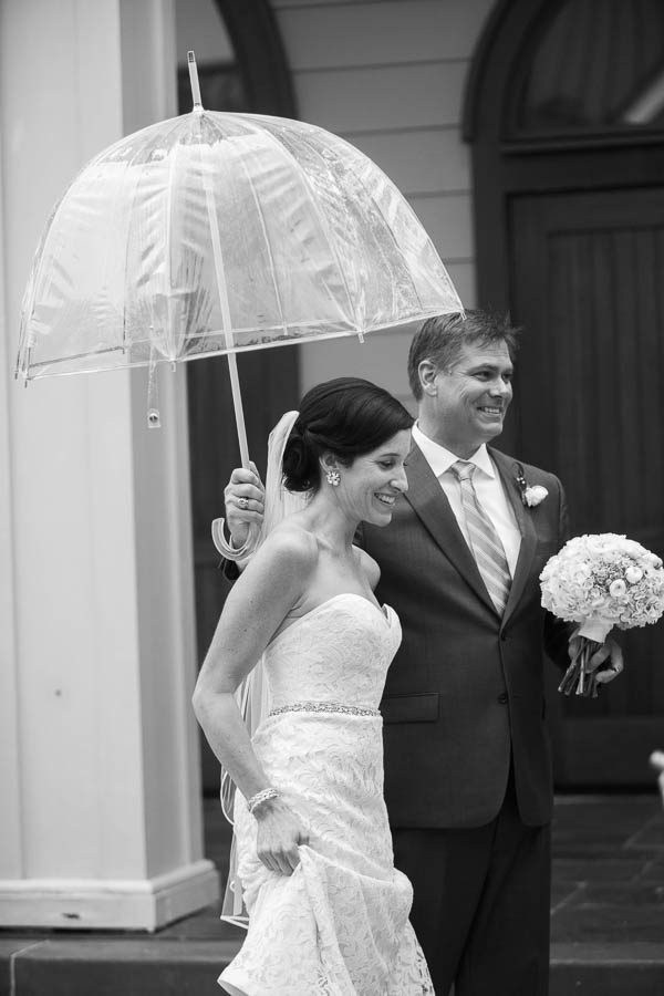 Groom holds umbrella for bride in rain, Church of the Holy Cross, Sullivans Island, Charleston, SC, Hurricane Joaquin. Kate Timbers Photography. katetimbers.com