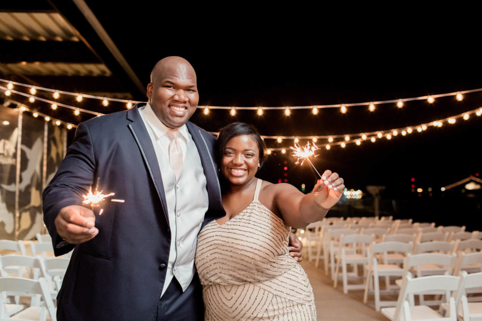 Bride poses with groom at night with sparklers, South Carolina Aquarium. Kate Timbers Photography. http://katetimbers.com