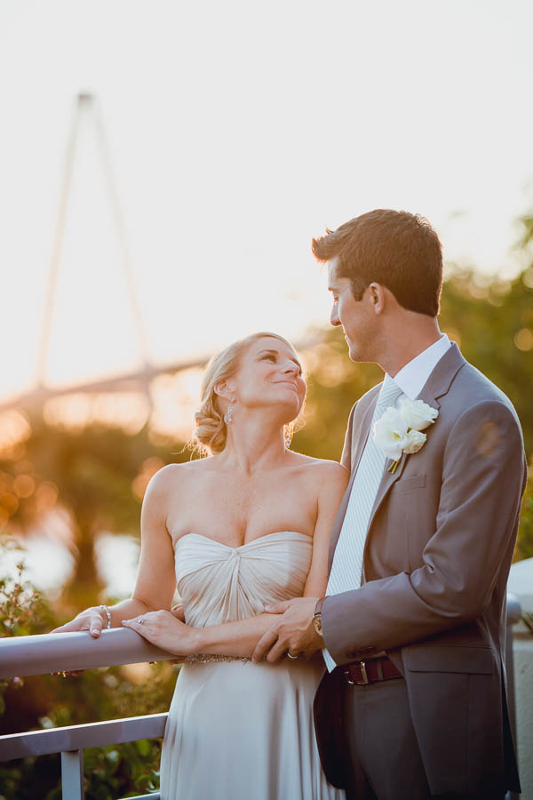 Bride and groom pose at sunset with Ravenel Bridge in background, Harborside East, Mt Pleasant, South Carolina. Kate Timbers Photography. http://katetimbers.com