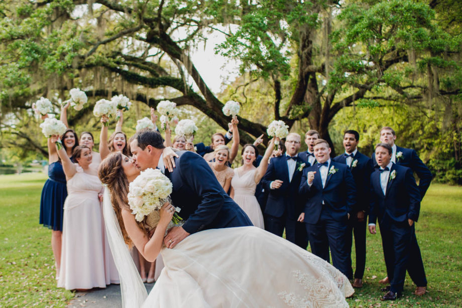 Bride and groom kiss while wedding party cheers, Brookgreen Gardens, Murrells Inlet, South Carolina. Kate Timbers Photography. http://katetimbers.com
