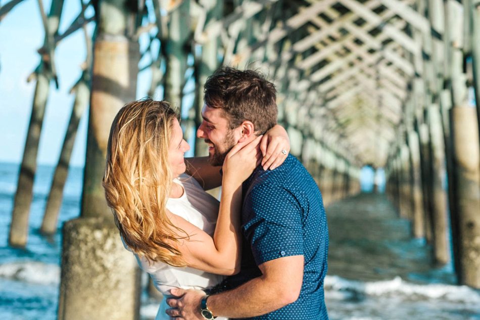Engaged Couple hugging under fishing pier, Folly beach in Charleston, South Carolina Kate Timbers Photography. http://katetimbers.com #katetimbersphotography // Charleston Photography // Inspiration