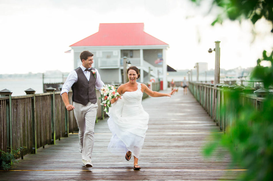 Bride and groom run down the docks of the Charleston Harbor, away from the rain. www.katetimbers.com