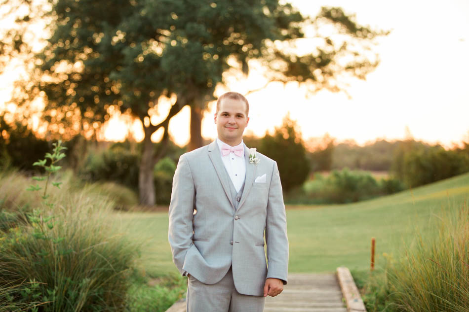 Groom stands in a field at sunset, Daniel Island Club. Kate Timbers Photography. http://katetimbers.com