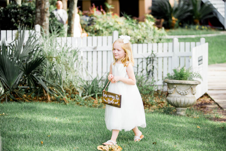 Flower girl walks up the aisle with a sign, I'on Creek Club, Mt Pleasant, South Carolina. Kate Timbers Photography. http://katetimbers.com