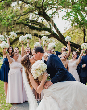 Bride and groom kiss while wedding party cheers, Brookgreen Gardens, Murrells Inlet, South Carolina. Kate Timbers Photography. http://katetimbers.com